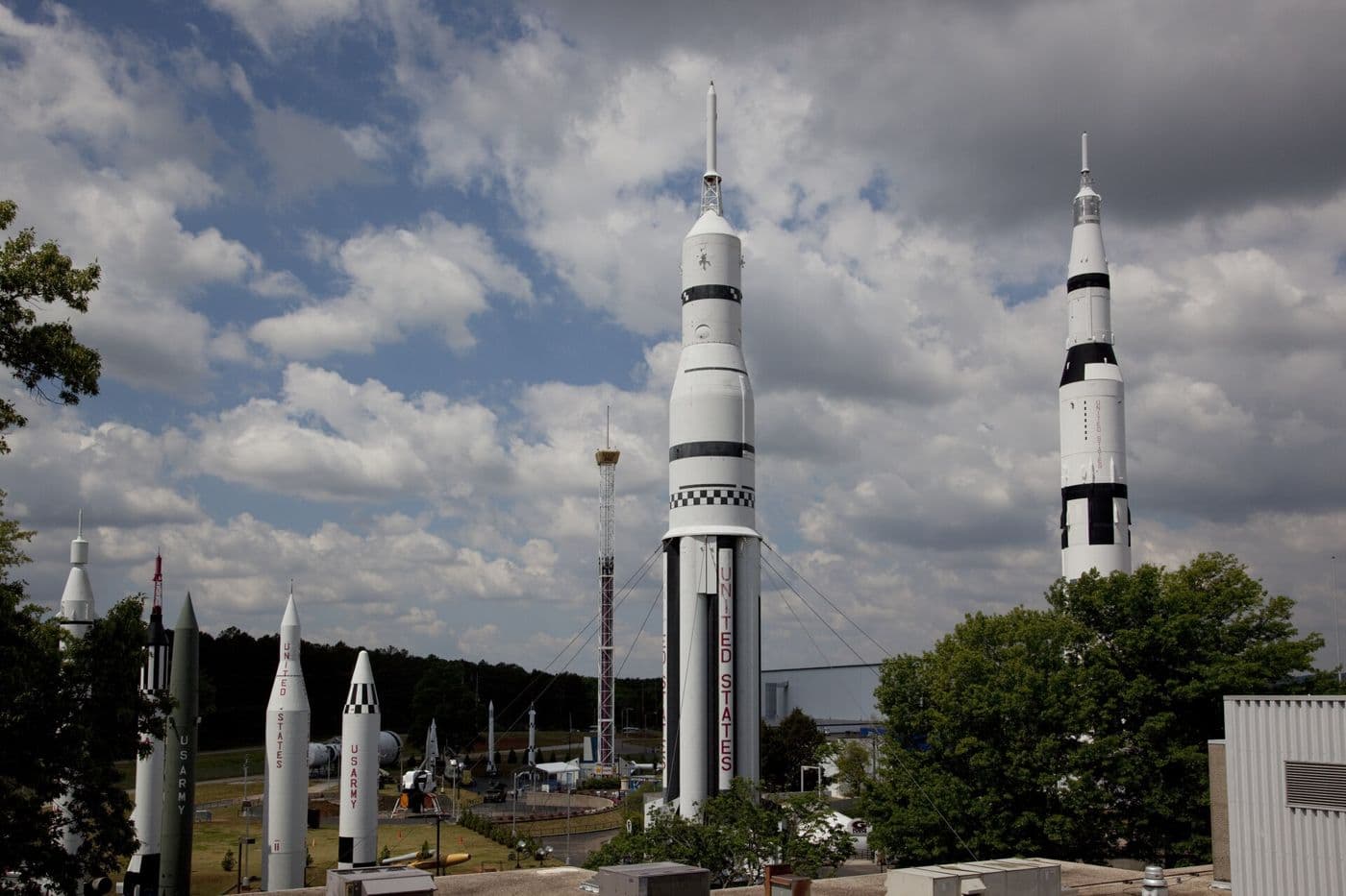 The rocket park at the U.S. Space & Rocket Center in Huntsville: tall white Saturn rockets and smaller missiles against a cloudy blue sky.